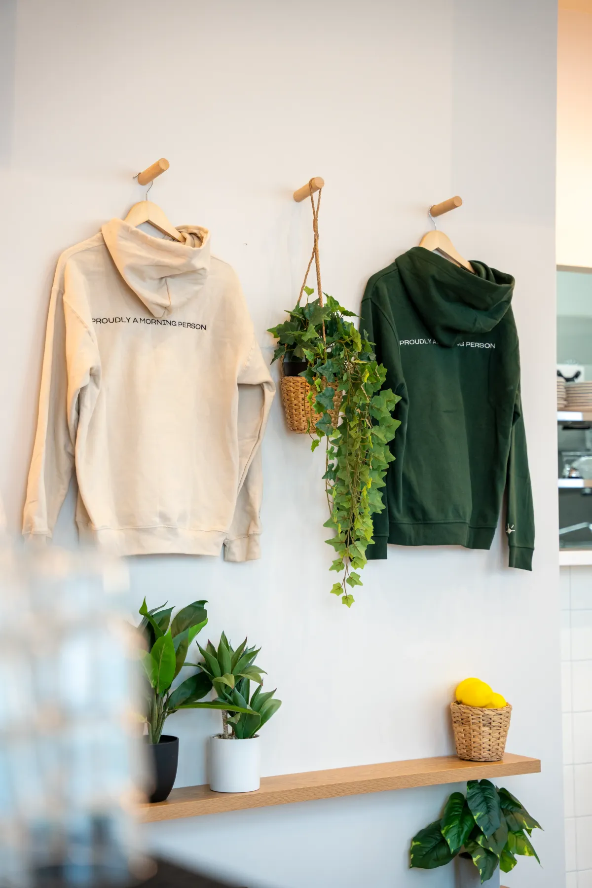 Eggstatic “Proudly a Morning Person” hoodies displayed on the wall with a hanging plant