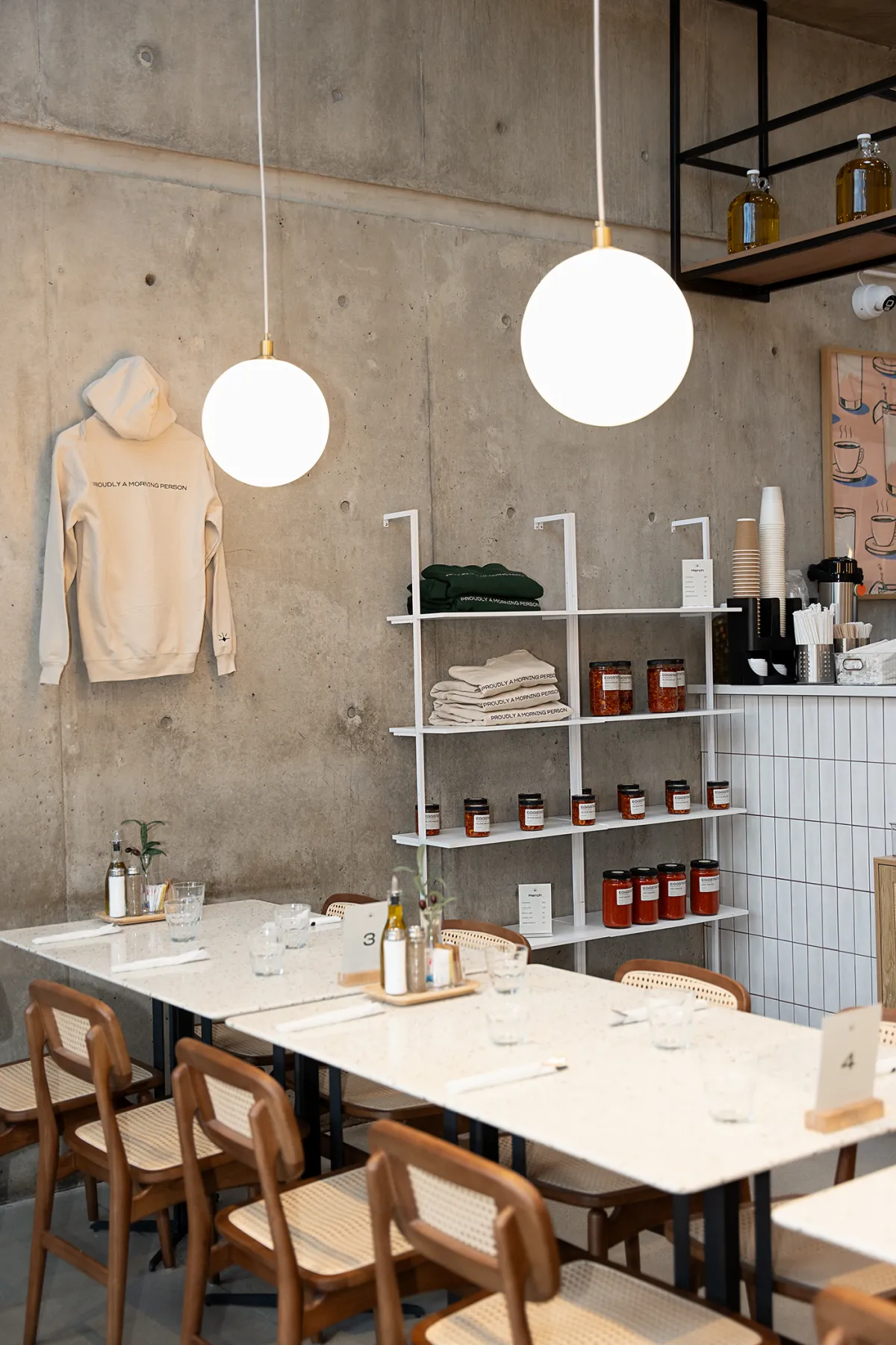 Eggstatic dining room with terrazzo tables, globe pendant lights and shelves of preserves