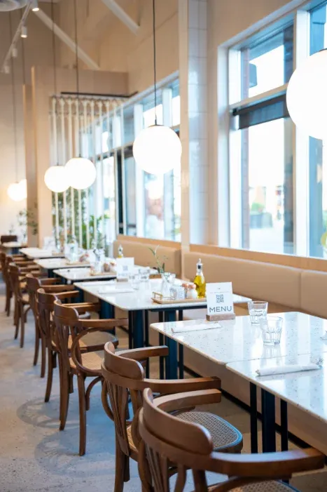 Sunlit row of marble tables and globe pendant lights at Eggstatic Oakville