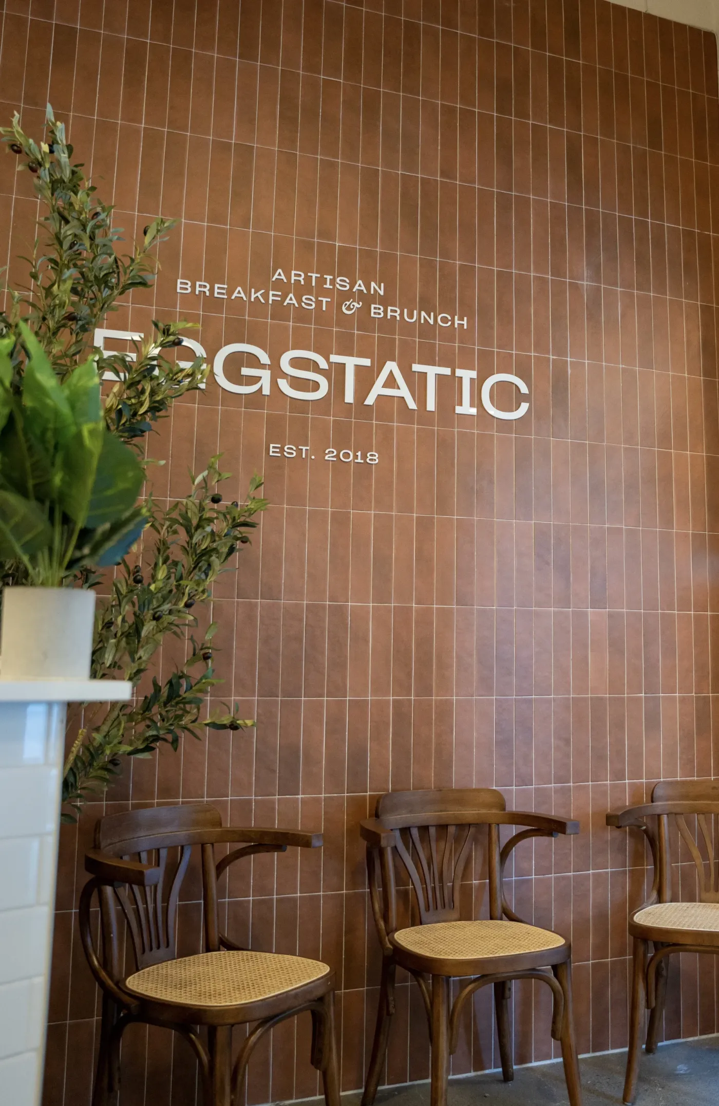 Eggstatic "Artisan Breakfast & Brunch — Est. 2018" wood-tile signage at the Downtown Toronto location