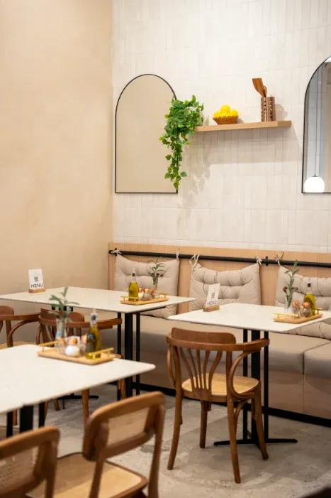 Two-top tables with banquette seating and arched mirrors at Eggstatic Oakville