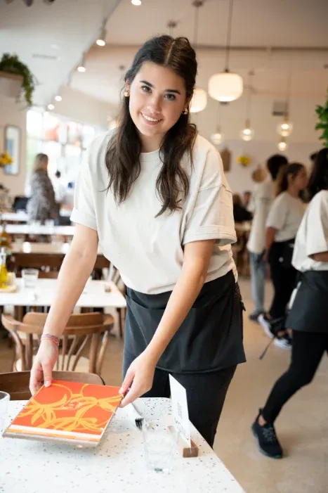 Smiling server placing a menu on a guest's table at Eggstatic London Ontario