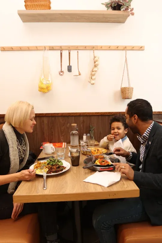 Family of three sharing a brunch in a booth at Eggstatic Montreal