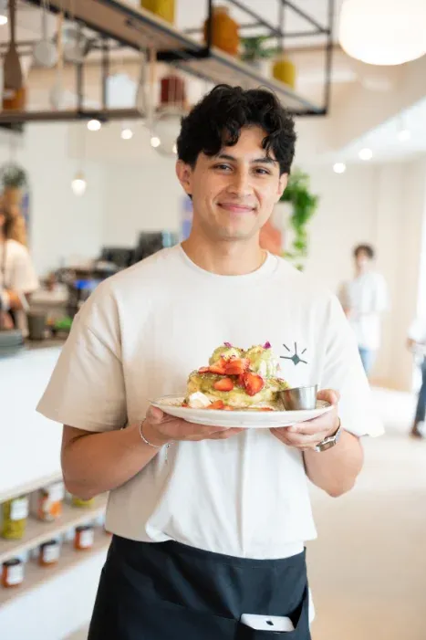 Smiling server holding a pistachio strawberry French toast plate at Eggstatic London Ontario