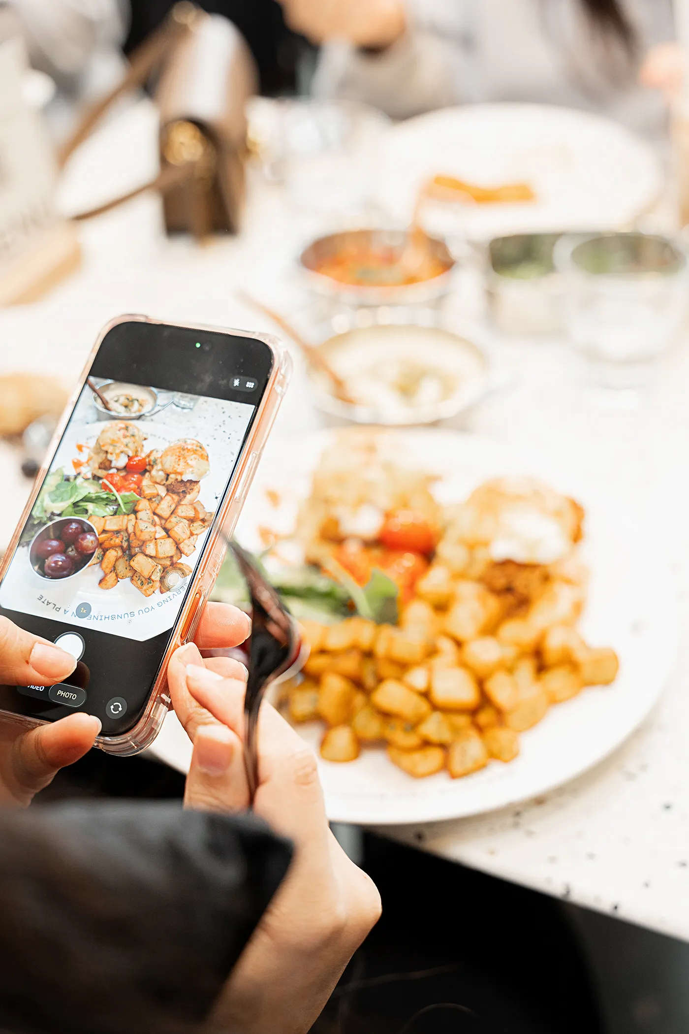 Guest photographing a brunch plate at an Eggstatic table