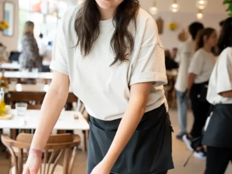 Smiling server placing a menu on a guest's table at Eggstatic London Ontario