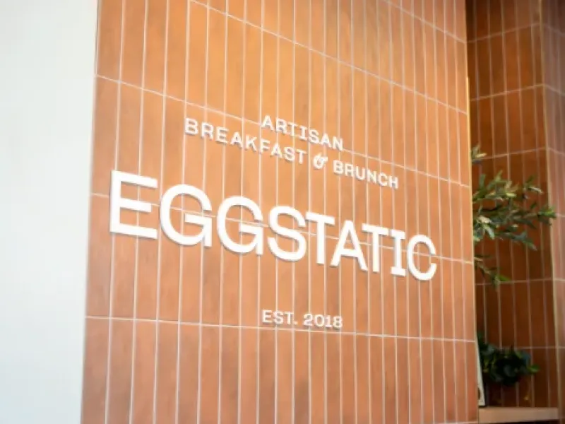 Eggstatic "Artisan Breakfast & Brunch — Est. 2018" wood-tile signage at the Oakville location