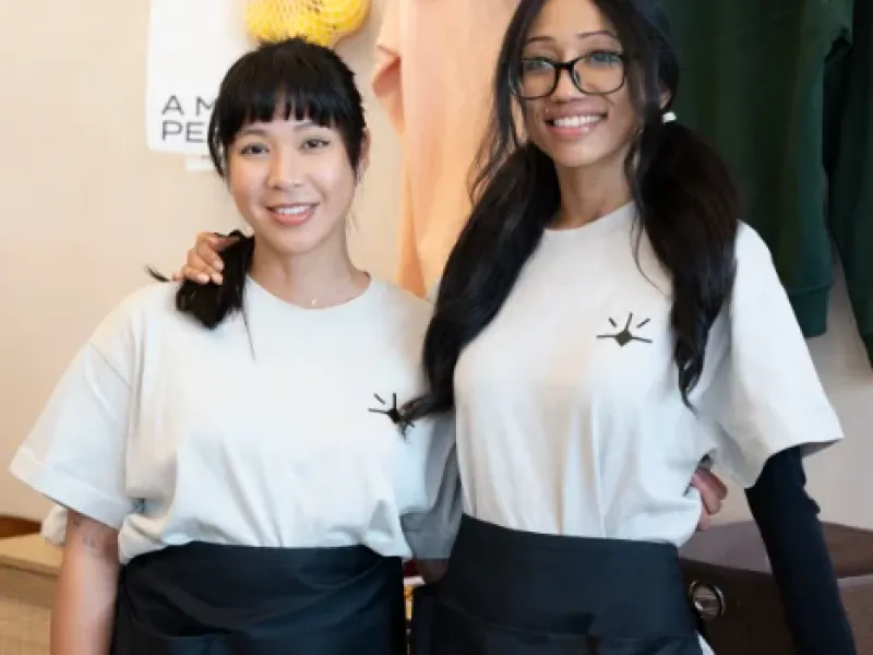 Smiling Eggstatic Oakville server pair in front of the Eggstatic merch hoodies