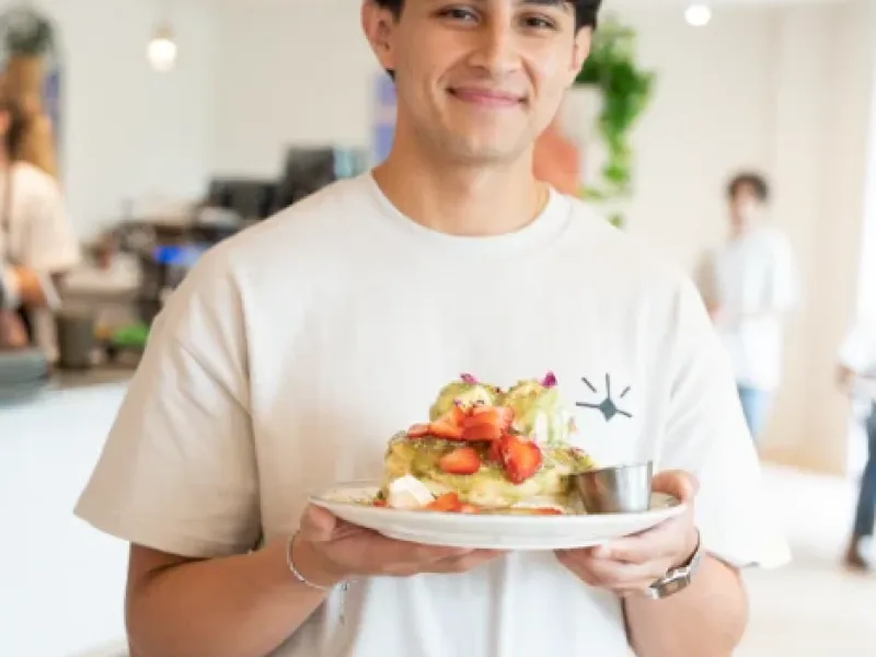 Smiling server holding a pistachio strawberry French toast plate at Eggstatic London Ontario