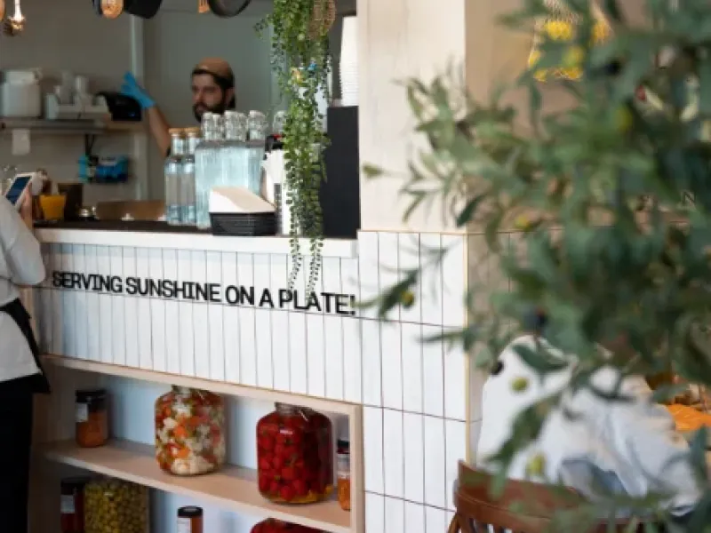 Barista at the service counter beneath the "Serving Sunshine on a Plate" tagline at Eggstatic Oakville